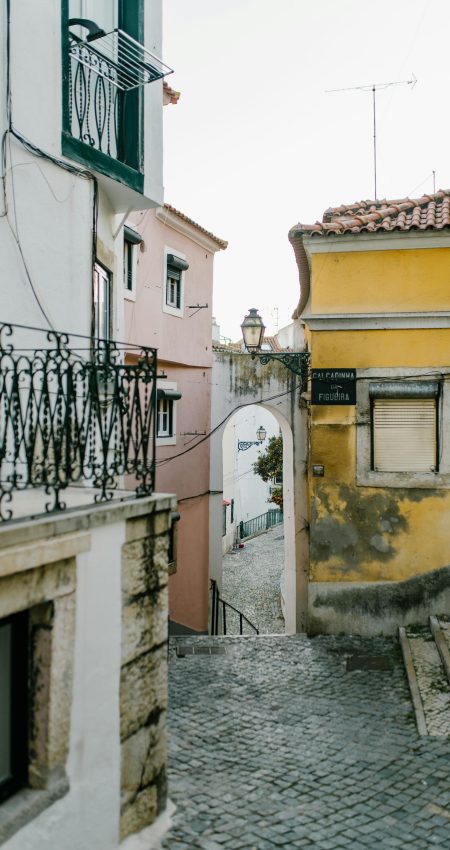 Charming Lisbon street with colorful buildings and cobblestone pathway, showcasing Portugal's architectural style.